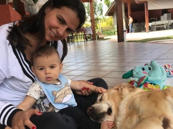 Ingrid sentada no chão com o filho Lorenzo e o cachorro da família
